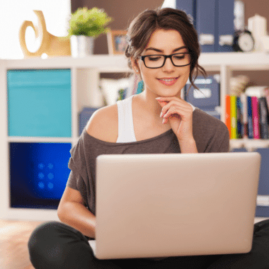 smiling-woman-using-laptop-on-floor-at-home-KTWBEPN.png